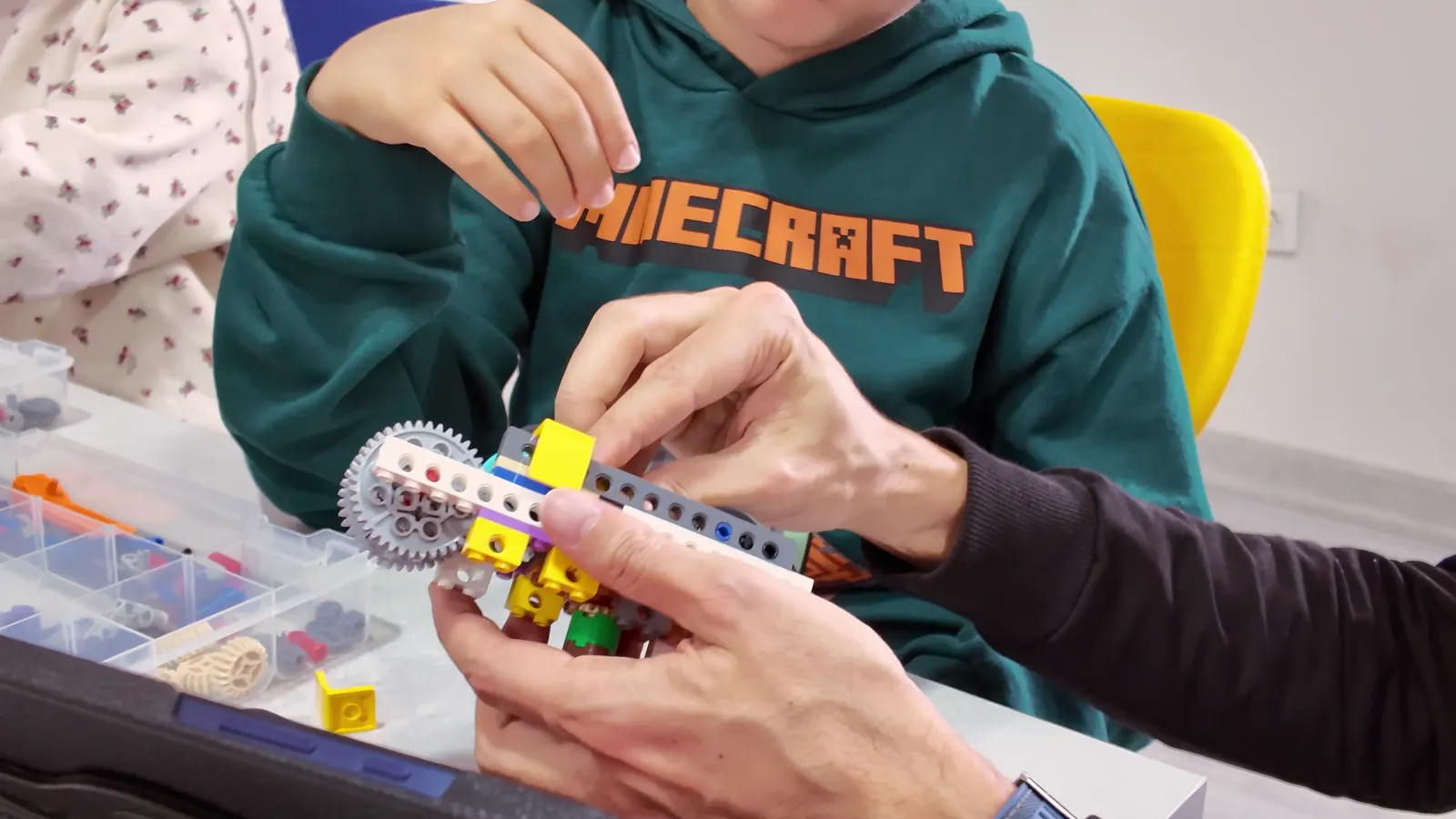 Çocuk eğitmenle birlikte LEGO dişli düzeneği kuruyor